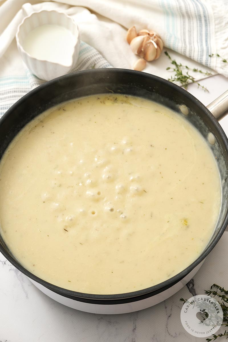 Butter, onion and garlic added to make the sauce with flour, salt, pepper, and thyme and chicken stock cooking in a pan.