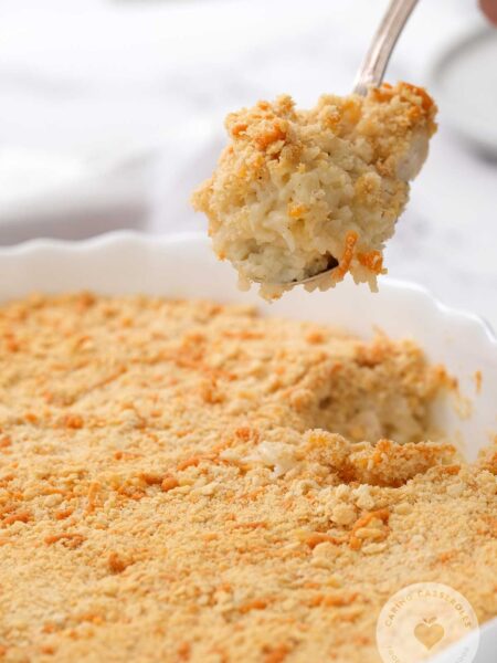 chicken and rice casserole in white serving dish with spoon taking scoop of the rich and creamy casserole out