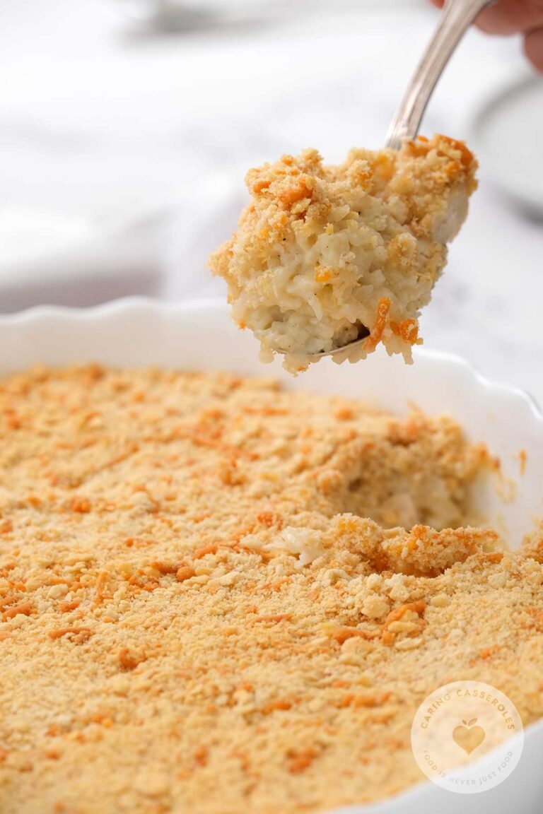 chicken and rice casserole in white serving dish with spoon taking scoop of the rich and creamy casserole out