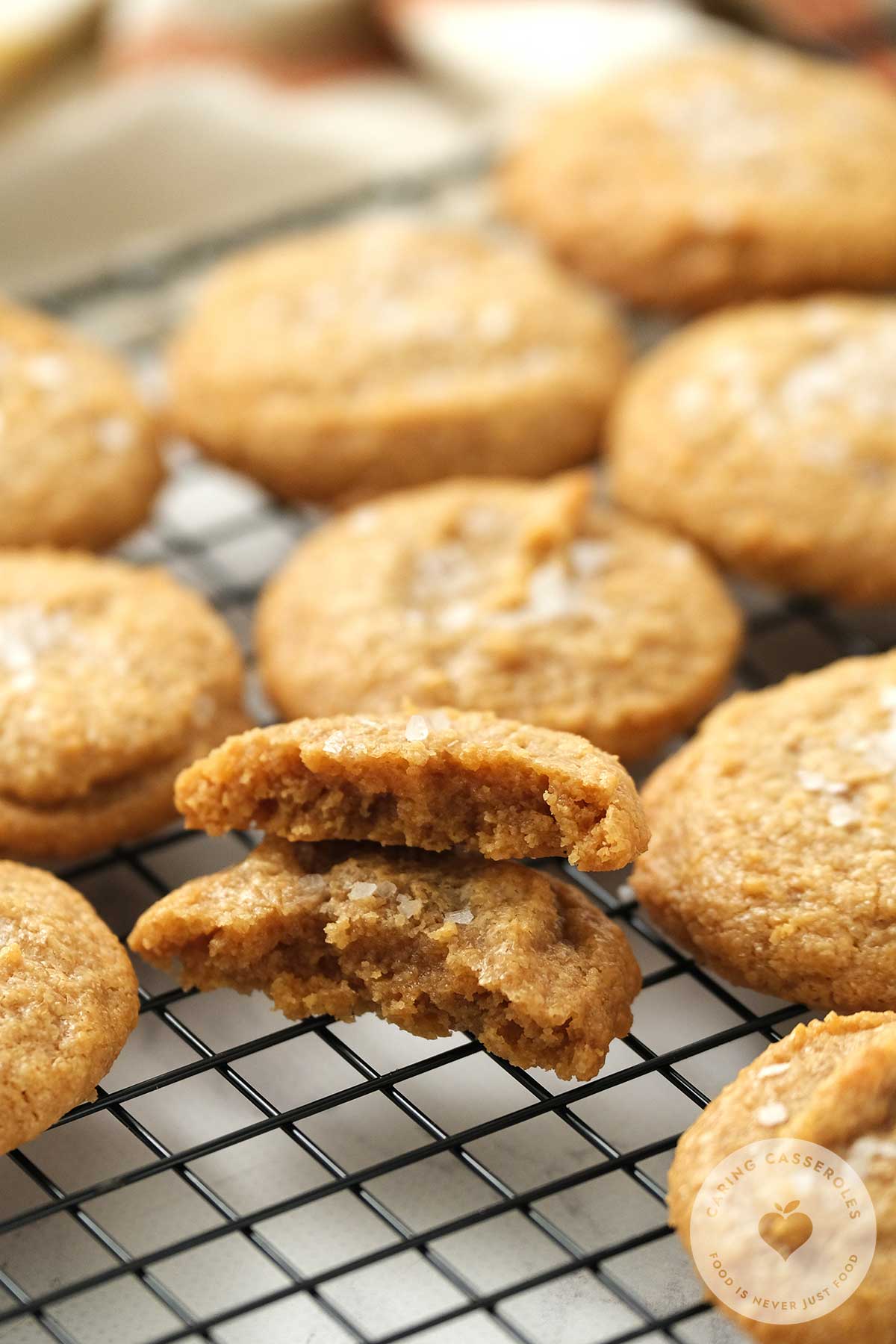 Dairy Free Gluten Free Peanut Butter cookies sitting on a baking rack with one broken in half. 