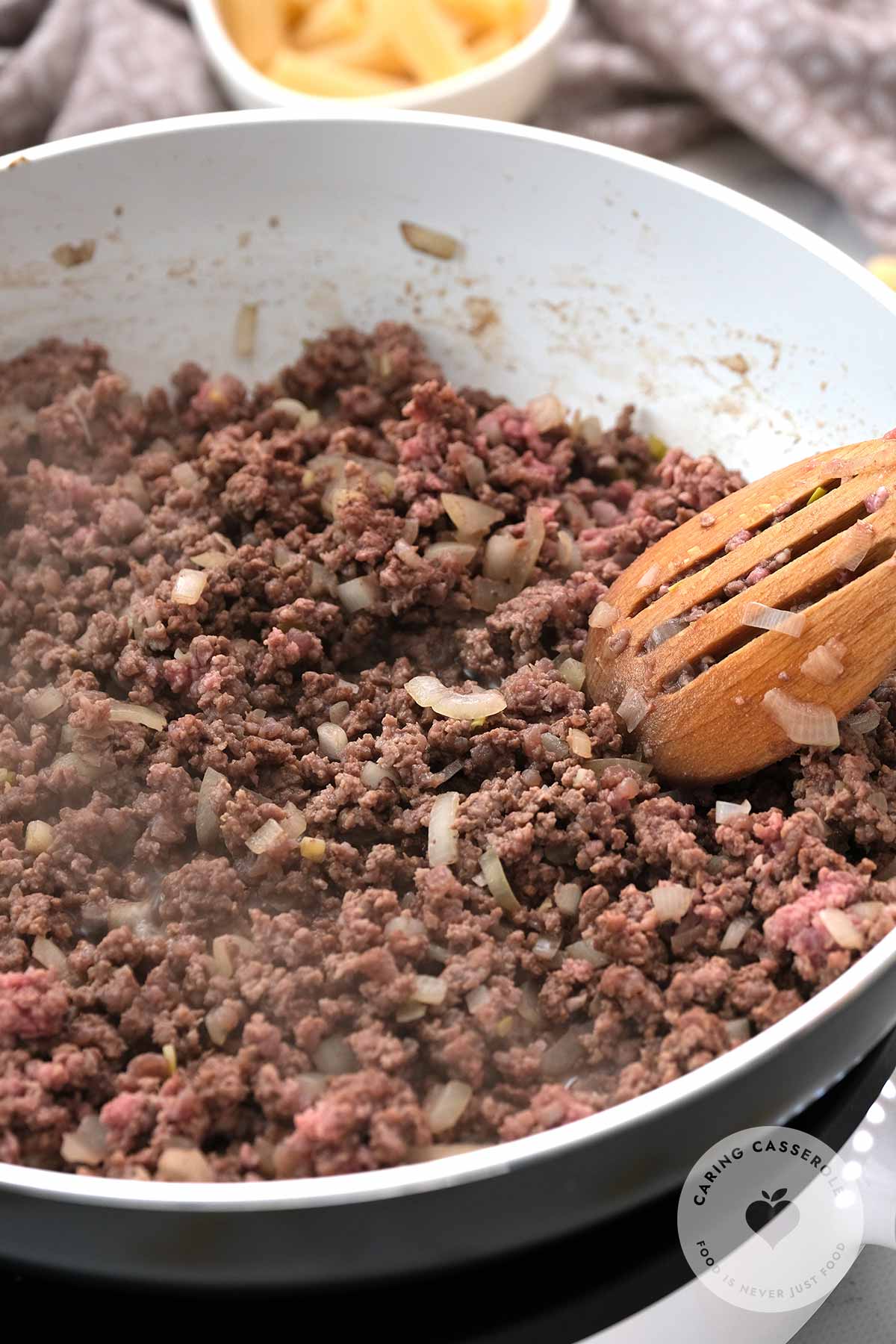 Chopped onion and ground beef cooking in a skillet over a medium heat.