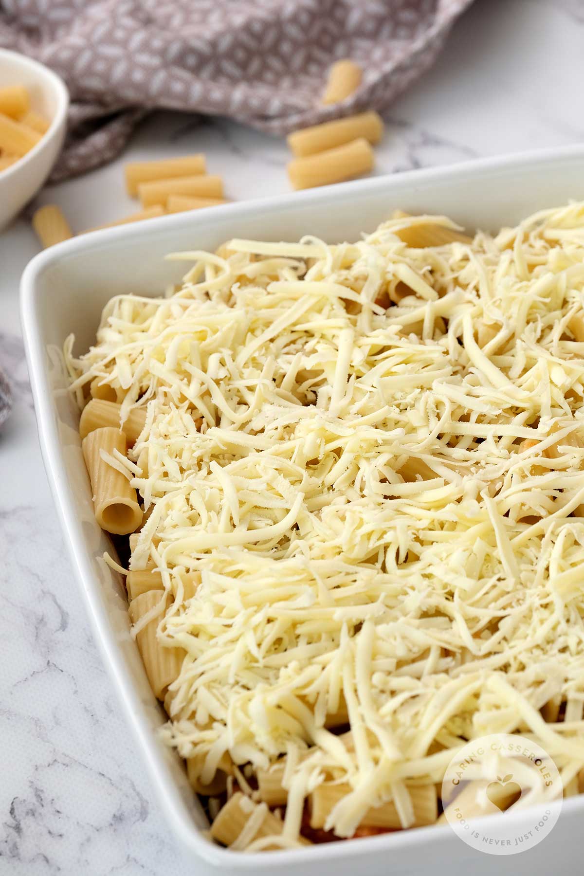 Top the ground beef, pasta, and provolone with helpings of parmesan cheese, covering the dish.