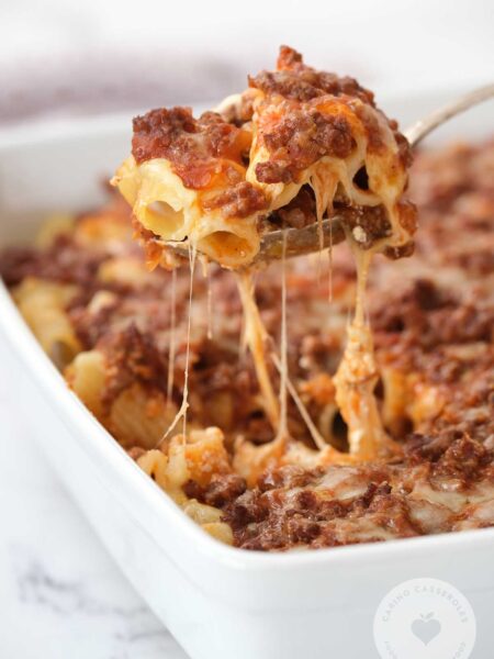 Penne pasta casserole being served from a large white dish.