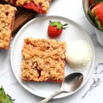 Ice cream and strawberry crumb bars served on a white plate.