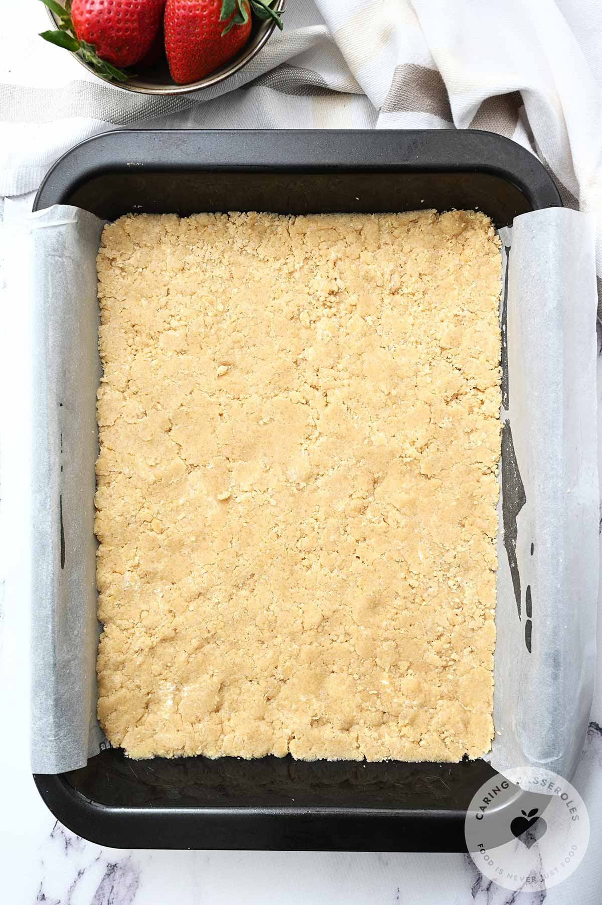 Half the crumb mixture is evenly pressed into a prepared baking dish