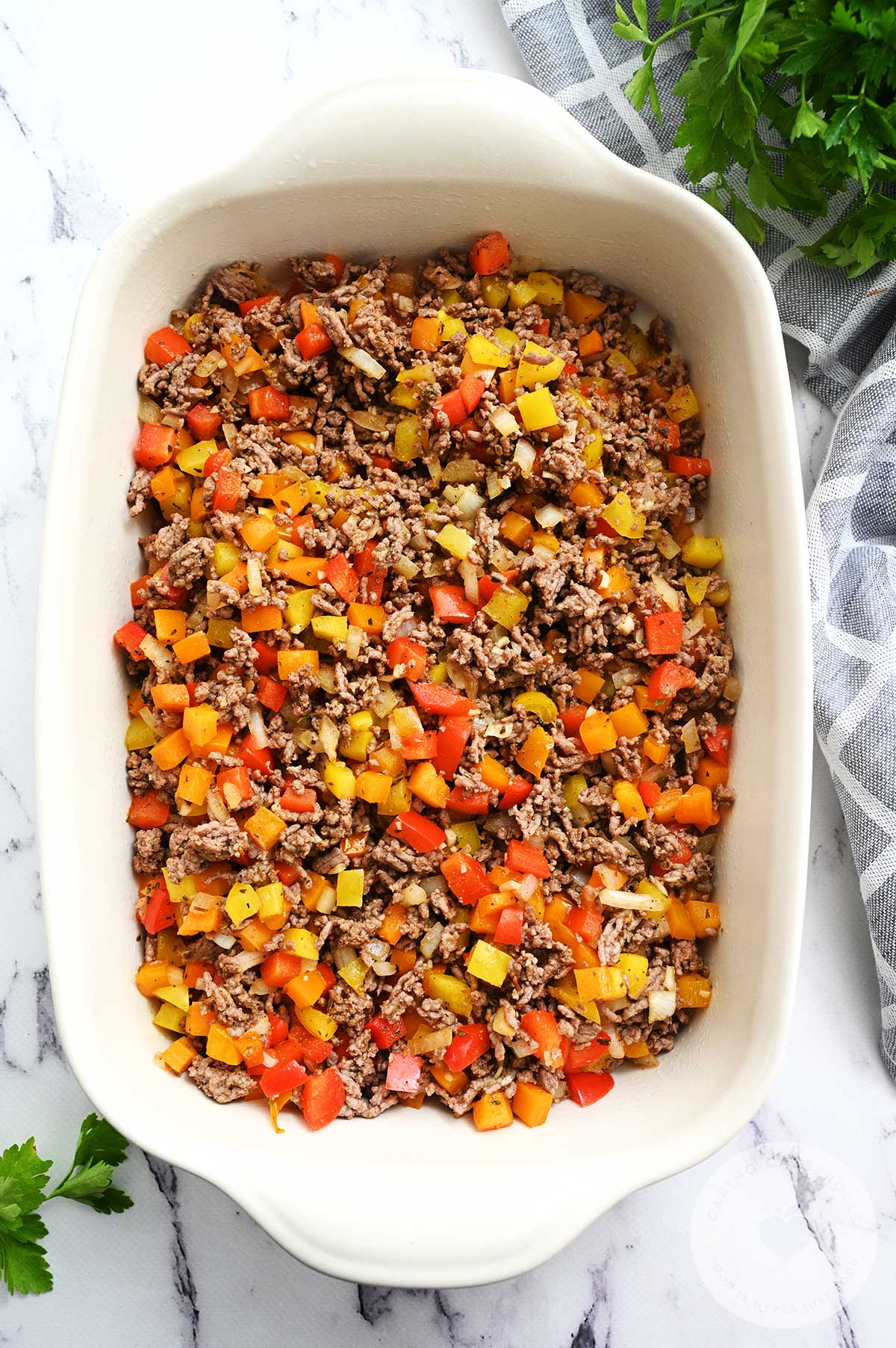 The beef mixture in the prepared casserole dish with added beef broth and diced tomatoes.