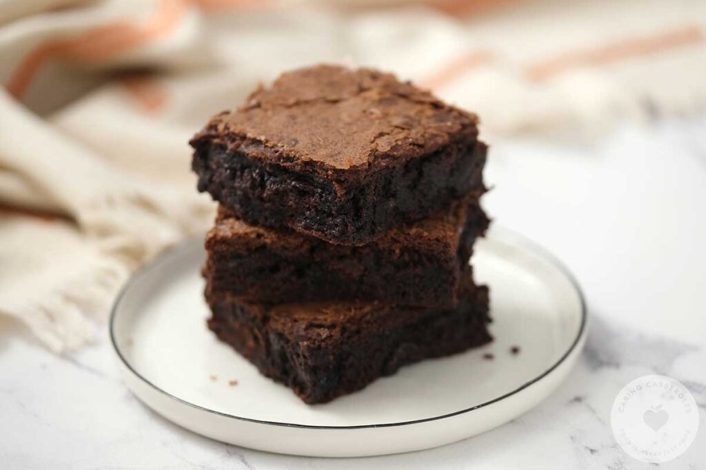 3 stacks of brownies on a white plate.