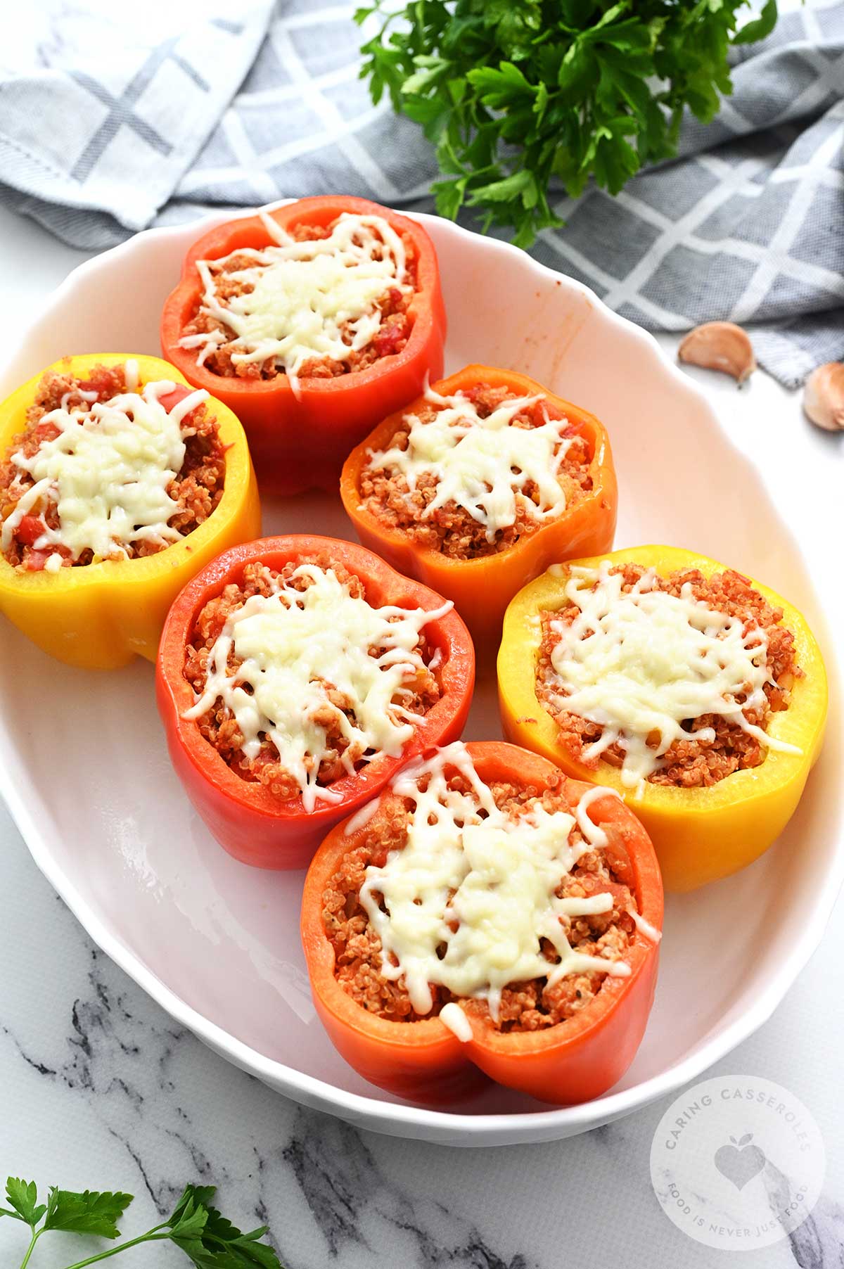 Peppers stuffed with filling, topped with cheese and ready to be baked in the oven.