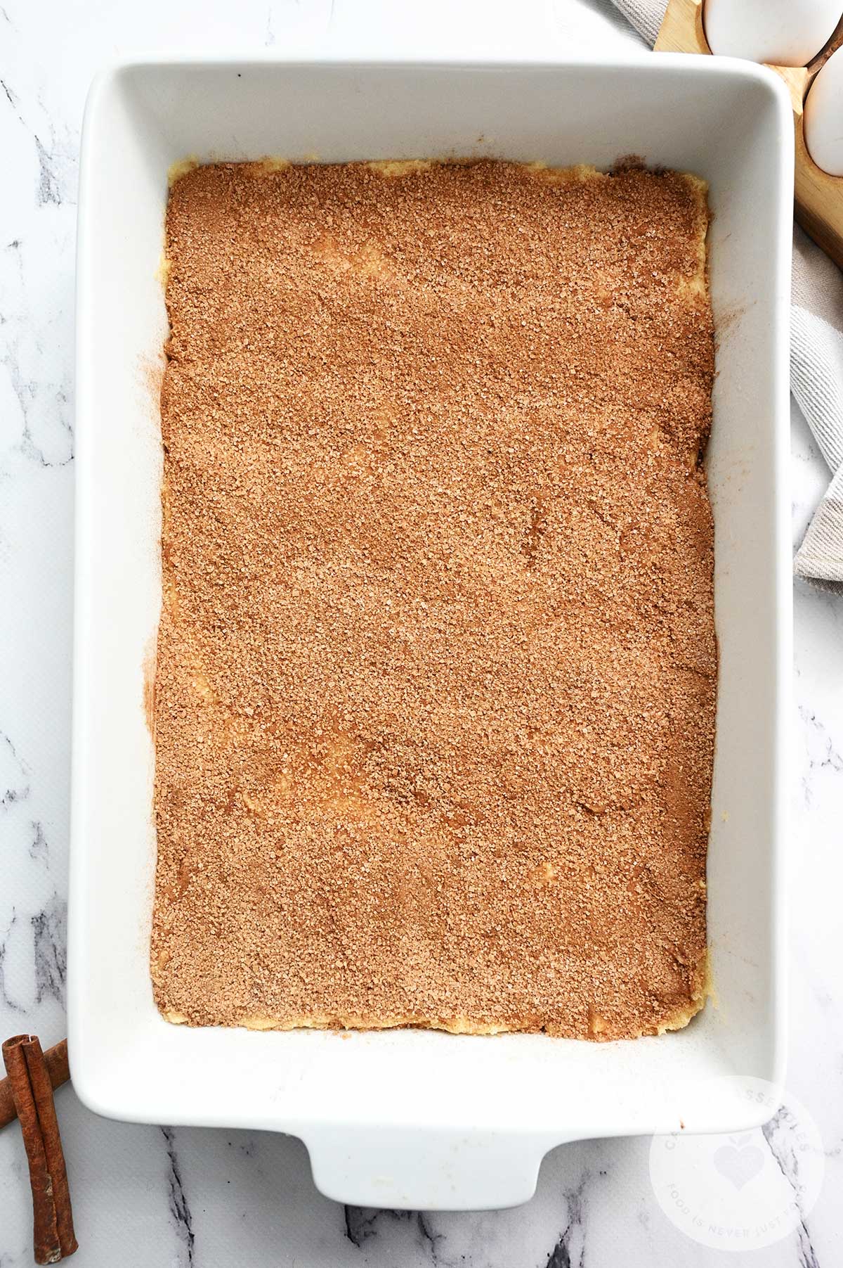 Cinnamon and sugar topping added to the batter in the baking dish.