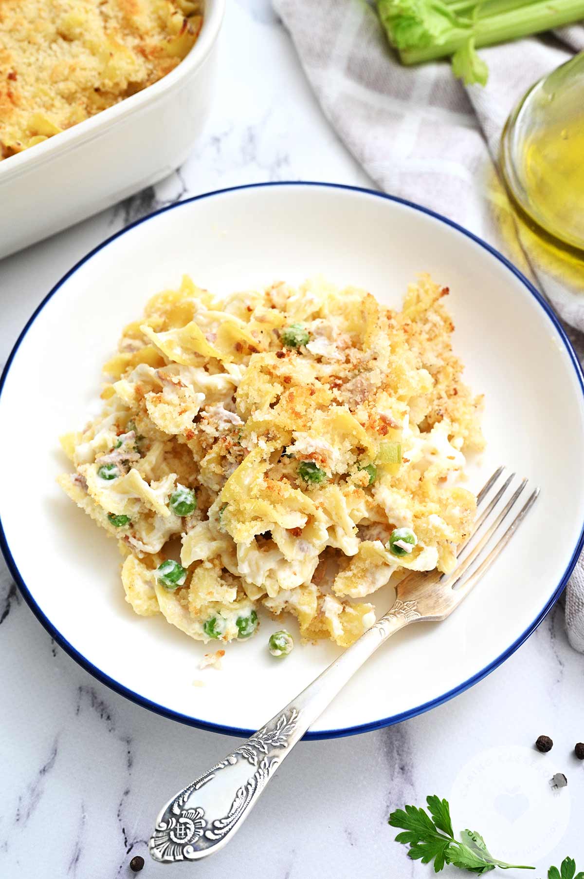 Tuna Noodle casserole on a white plate, with a fork, and made from a recipe from Caring Casseroles.