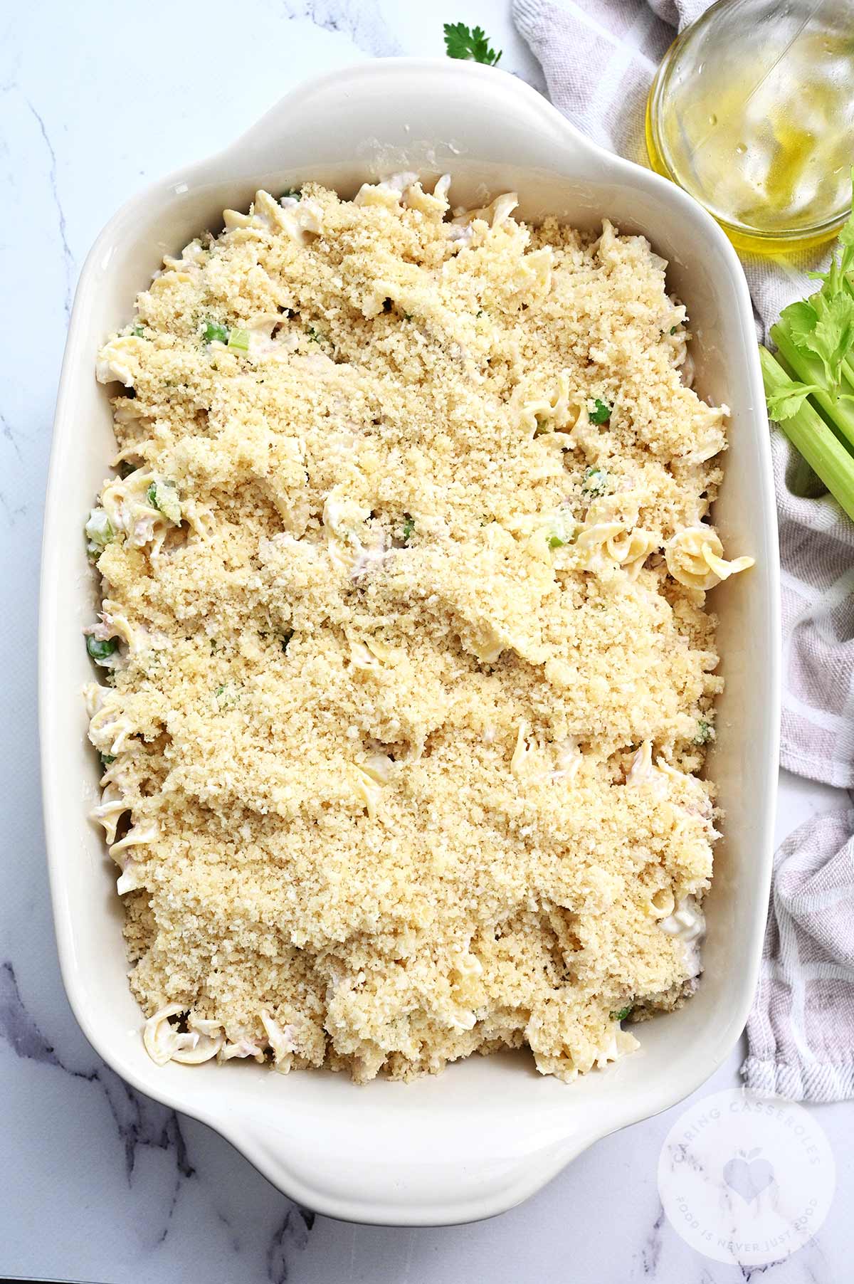 Tuna Noodle casserole ingredients transferred to a baking dish and topped with breadcrumbs.