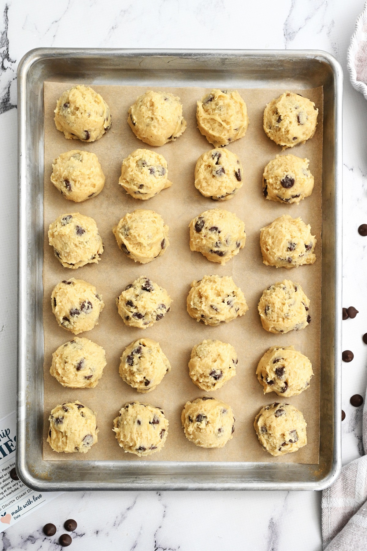 Cookie dough balls on a baking sheet placed on parchment paper, ready to chill in the refigerator. 